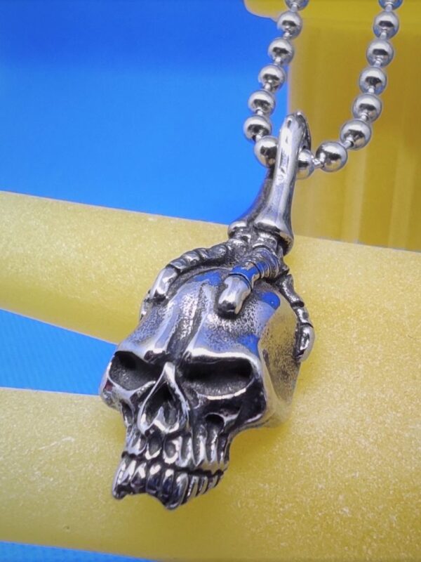 Pendentif gothique acier griffe squelette tenant une tête de mort, style gothique rock biker punk