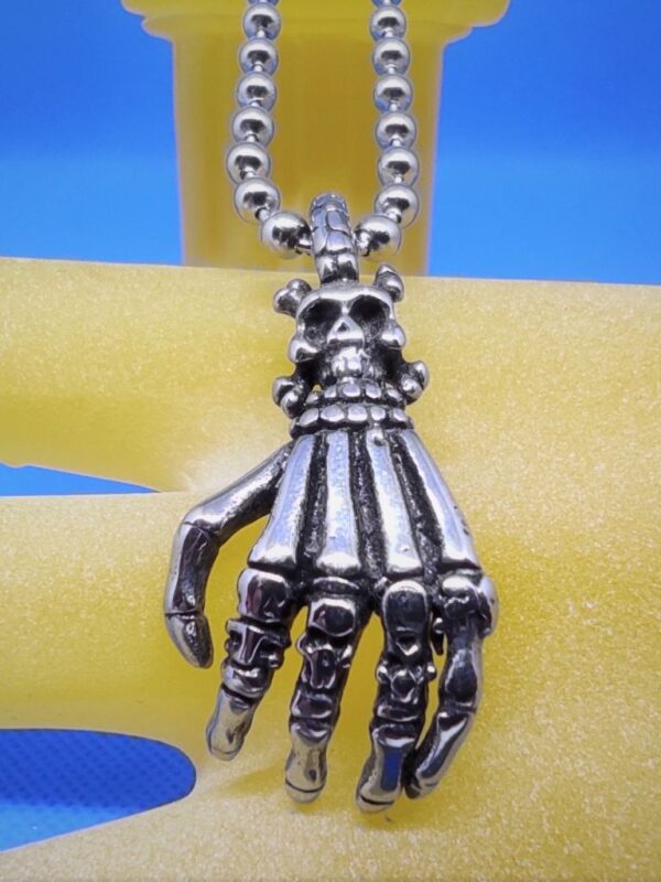 Pendentif gothique acier main squelette surmontée d'un Jolly Roger, style gothique rock biker punk